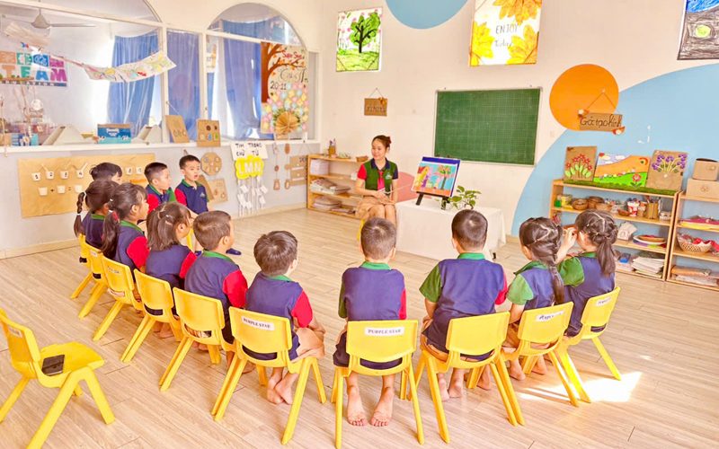 Cả lớp ngồi ghế vàng thành vòng tròn trong phòng học nhiều màu